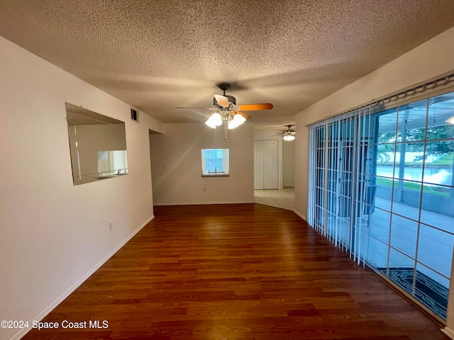 spare room featuring ceiling fan, dark wood-type flooring, and a textured ceiling