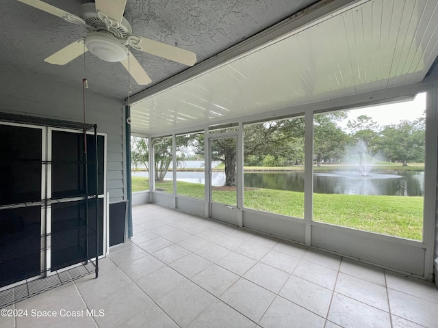 unfurnished sunroom with ceiling fan and a water view