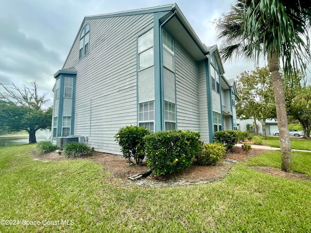 view of side of property with a lawn and cooling unit