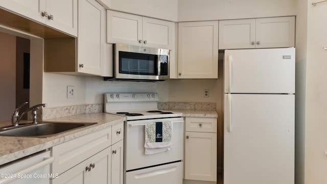 kitchen with white cabinets, light stone countertops, white appliances, and sink