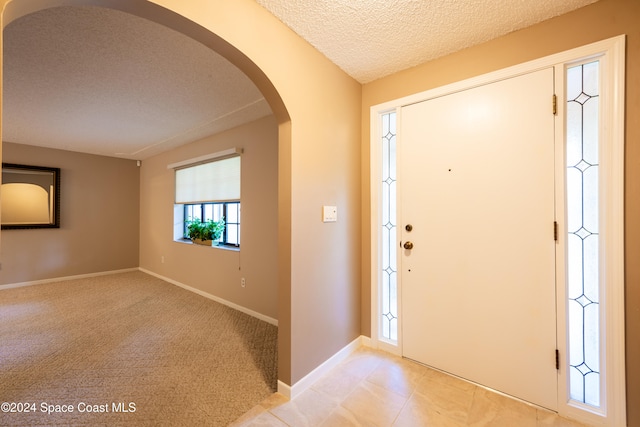 foyer with light carpet and a textured ceiling