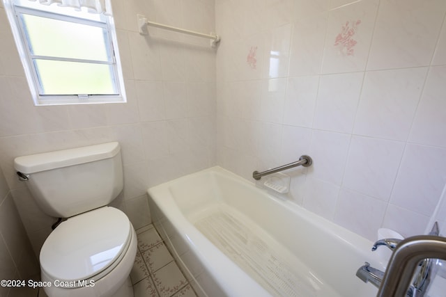 bathroom with tile walls, a bathing tub, and toilet