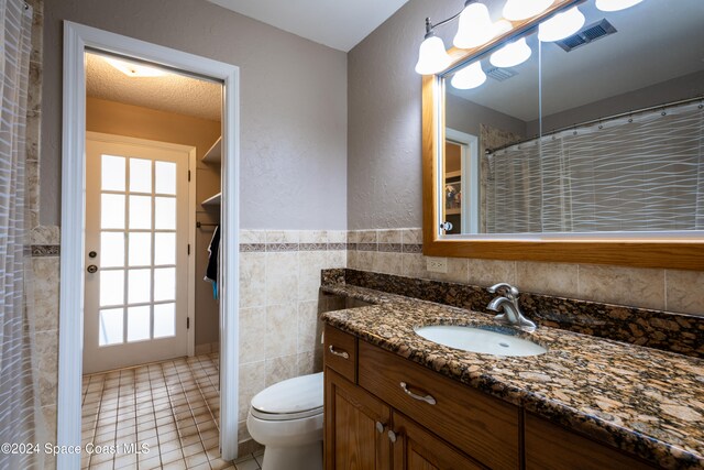 bathroom with tile patterned floors, toilet, tile walls, and plenty of natural light