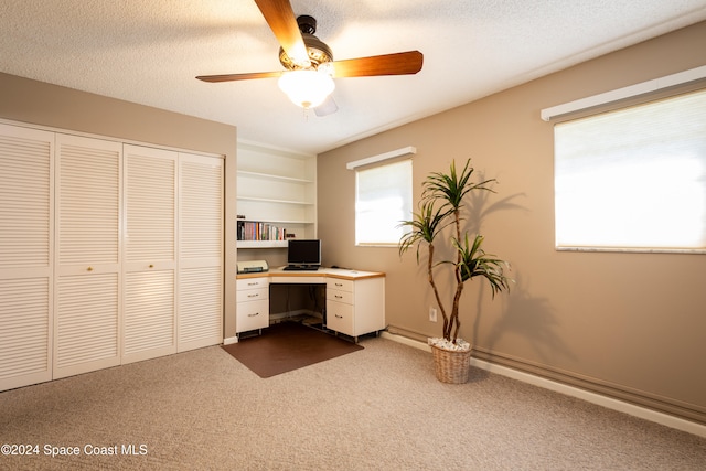 unfurnished office with ceiling fan, a textured ceiling, and dark colored carpet