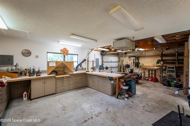 miscellaneous room with electric panel, a workshop area, and a textured ceiling