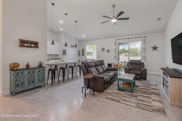 tiled living room with ceiling fan, sink, and high vaulted ceiling