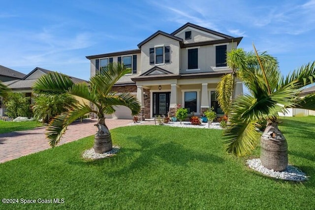 view of front of house with decorative driveway, a garage, a front lawn, and stucco siding