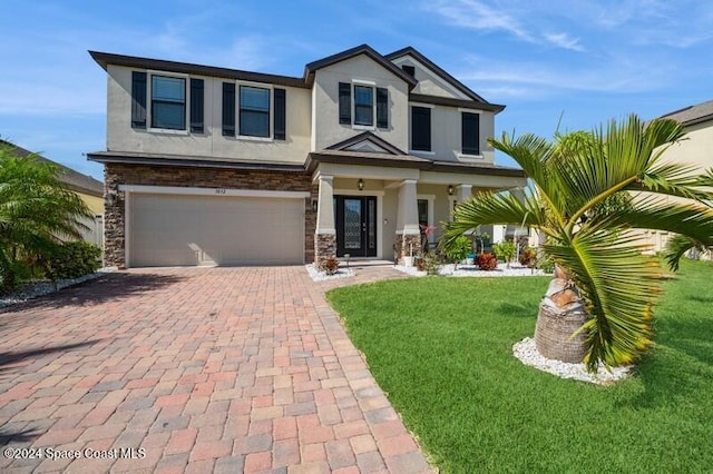 craftsman inspired home with stucco siding, decorative driveway, stone siding, a front yard, and an attached garage