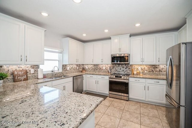 kitchen featuring a sink, stainless steel appliances, light tile patterned flooring, and white cabinetry