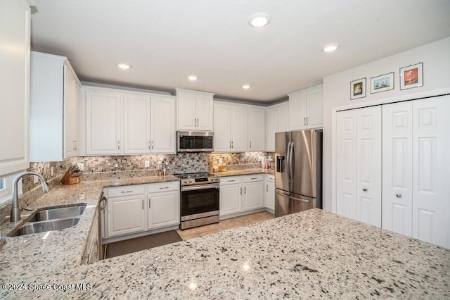 kitchen featuring decorative backsplash, white cabinetry, stainless steel appliances, and a sink