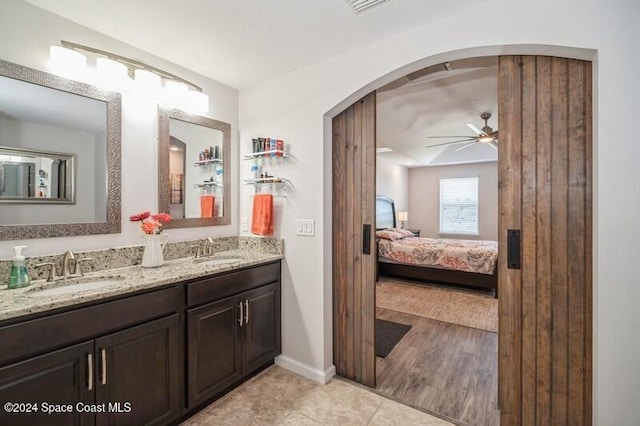 full bath with double vanity, ensuite bathroom, a ceiling fan, and a sink