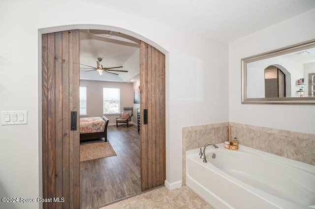 ensuite bathroom featuring baseboards, ensuite bathroom, a bath, and a ceiling fan