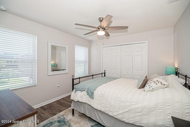 bedroom featuring a closet, multiple windows, baseboards, and wood finished floors