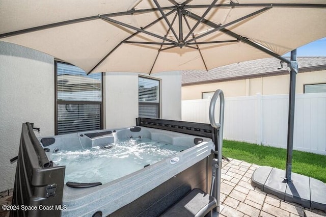 view of patio with a hot tub and fence