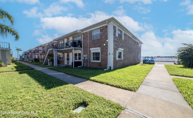 view of front facade featuring a front lawn and a balcony