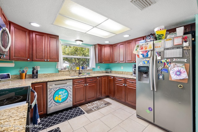 kitchen featuring sink, a textured ceiling, stainless steel appliances, light stone counters, and light tile patterned floors