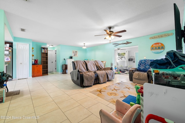 living room with ceiling fan, a textured ceiling, and light tile patterned floors