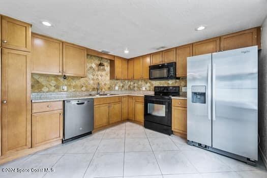 kitchen with backsplash, sink, light tile patterned floors, and black appliances