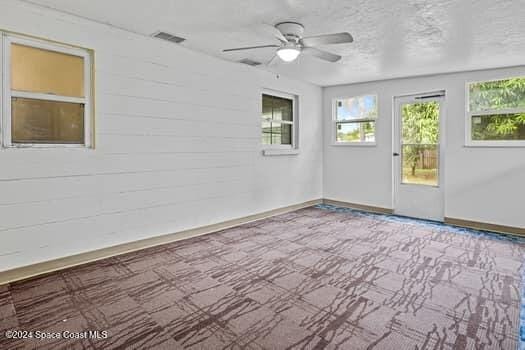 unfurnished room with ceiling fan and wooden walls