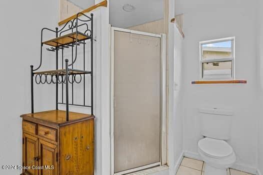 bathroom featuring tile patterned flooring, toilet, and walk in shower