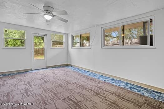 unfurnished sunroom featuring ceiling fan and a healthy amount of sunlight