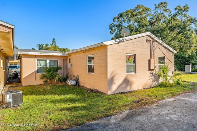 view of side of property with central AC and a lawn