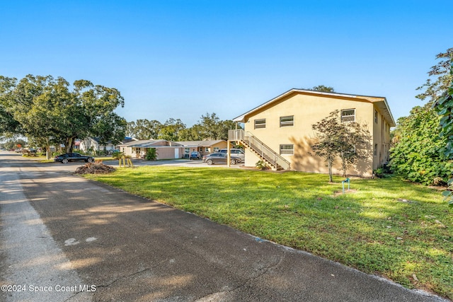 view of front of property with stucco siding, a front yard, and stairway