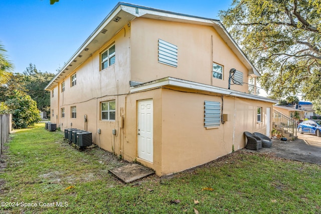 rear view of property featuring a yard and central air condition unit