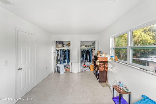 bedroom featuring two closets and light tile patterned floors