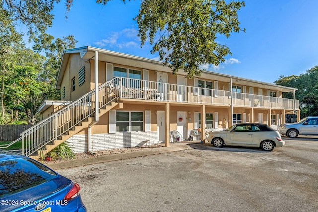 view of front of house featuring stucco siding, uncovered parking, and stairs