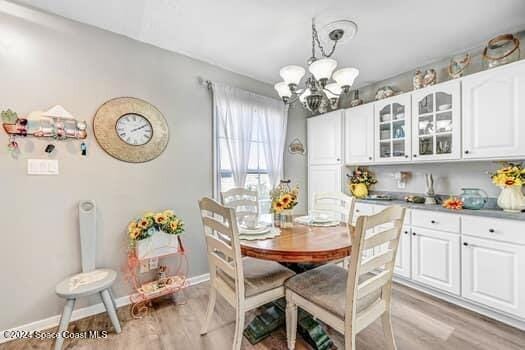 927 Jamestown Ave # 105, Indian Harbour Beach, FL 32937 - dining room with a chandelier, light wood finished floors, and baseboards