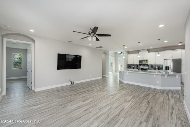 unfurnished living room featuring light hardwood / wood-style flooring, sink, and ceiling fan