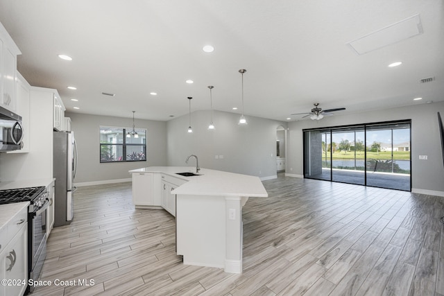 kitchen featuring stainless steel appliances, hanging light fixtures, plenty of natural light, and an island with sink