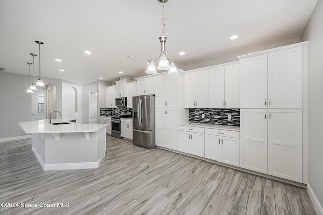 kitchen with white cabinetry, decorative light fixtures, a kitchen island with sink, and stainless steel appliances