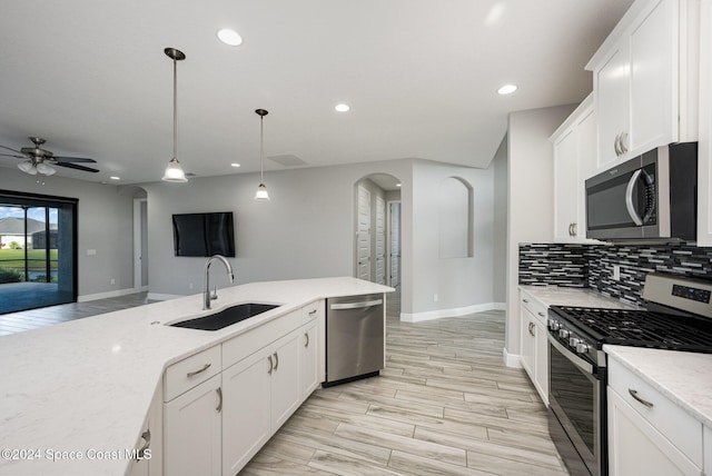 kitchen with appliances with stainless steel finishes, white cabinets, sink, and decorative light fixtures