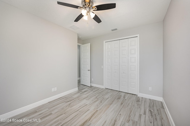 unfurnished bedroom featuring a closet, a textured ceiling, light wood-type flooring, and ceiling fan