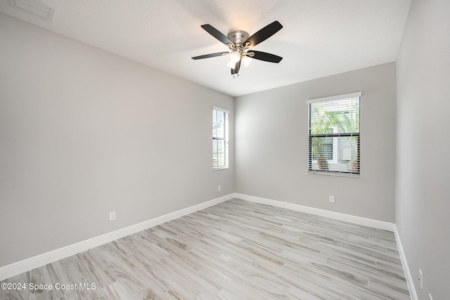 spare room with light wood-type flooring, plenty of natural light, and ceiling fan