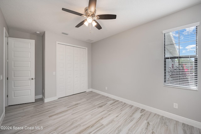 unfurnished bedroom with light hardwood / wood-style flooring, a closet, a textured ceiling, and ceiling fan