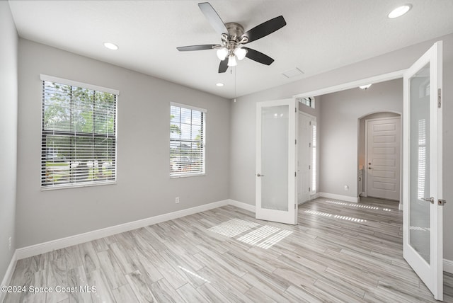 spare room featuring french doors, light hardwood / wood-style floors, a textured ceiling, and ceiling fan