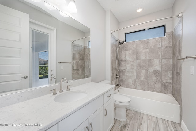 full bathroom with vanity, tiled shower / bath combo, hardwood / wood-style flooring, and toilet