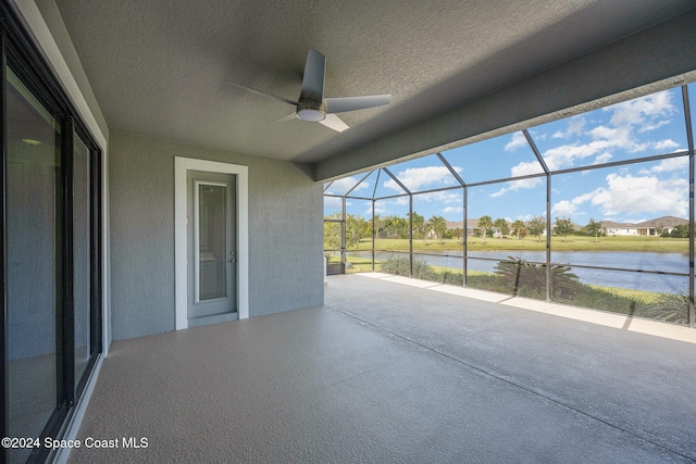 view of patio featuring a lanai, a water view, and ceiling fan