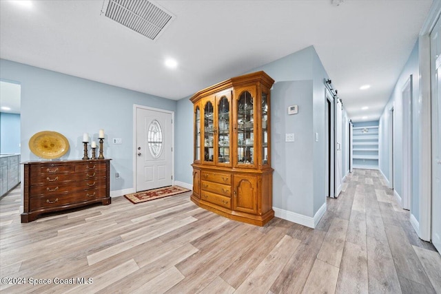 corridor featuring a barn door and light hardwood / wood-style flooring