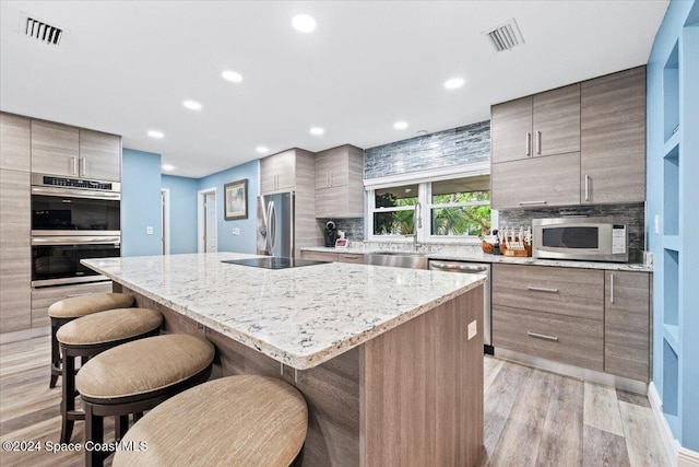 kitchen with a center island, light stone countertops, light hardwood / wood-style floors, and appliances with stainless steel finishes