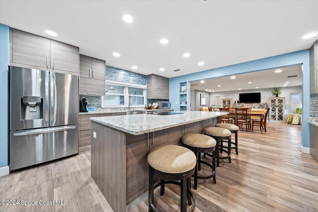 kitchen featuring a breakfast bar, stainless steel fridge, a center island, and light hardwood / wood-style floors