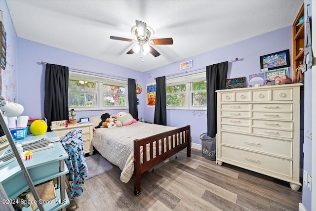 bedroom featuring ceiling fan, light hardwood / wood-style floors, and a textured ceiling