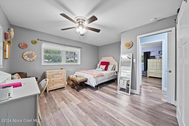 bedroom with a textured ceiling, light hardwood / wood-style flooring, and ceiling fan