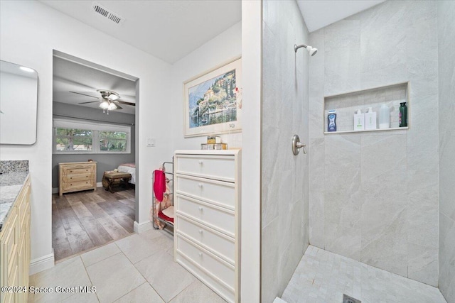 bathroom featuring ceiling fan, vanity, wood-type flooring, and tiled shower