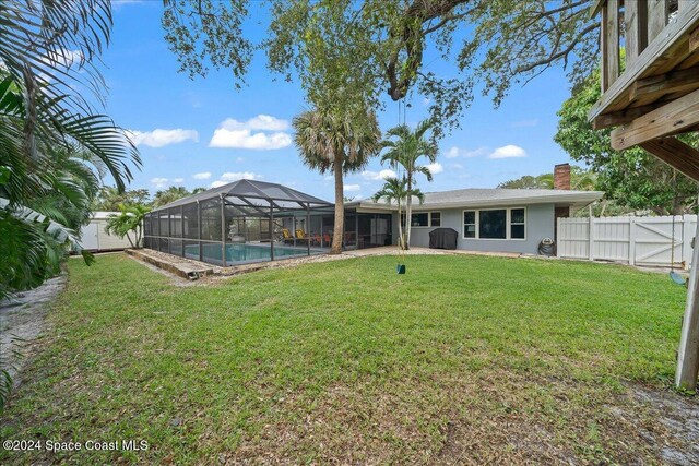 view of yard featuring a fenced in pool and glass enclosure