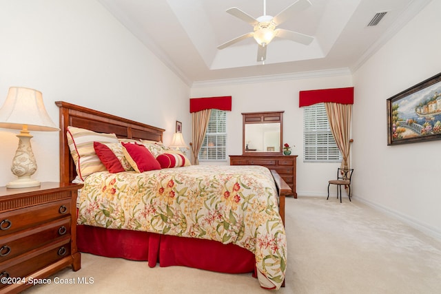 bedroom with ornamental molding, light carpet, a tray ceiling, and ceiling fan