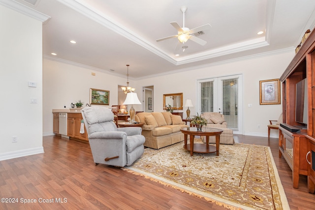 living room with french doors, hardwood / wood-style floors, crown molding, a raised ceiling, and ceiling fan with notable chandelier